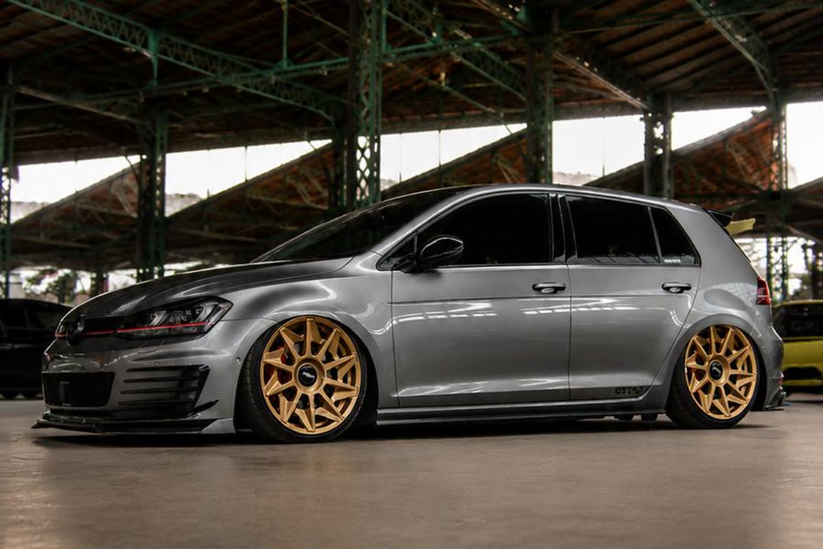 Volkswagen Golf GTI gris muy rebajado con llantas doradas, ejemplo de estilo stance